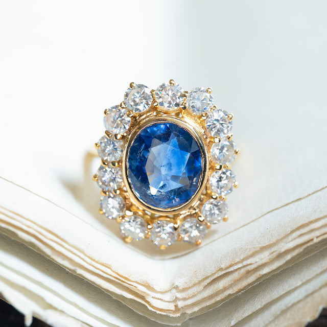 Vintage 1960s French sapphire and diamond cluster ring with oval blue sapphire surrounded by diamonds.