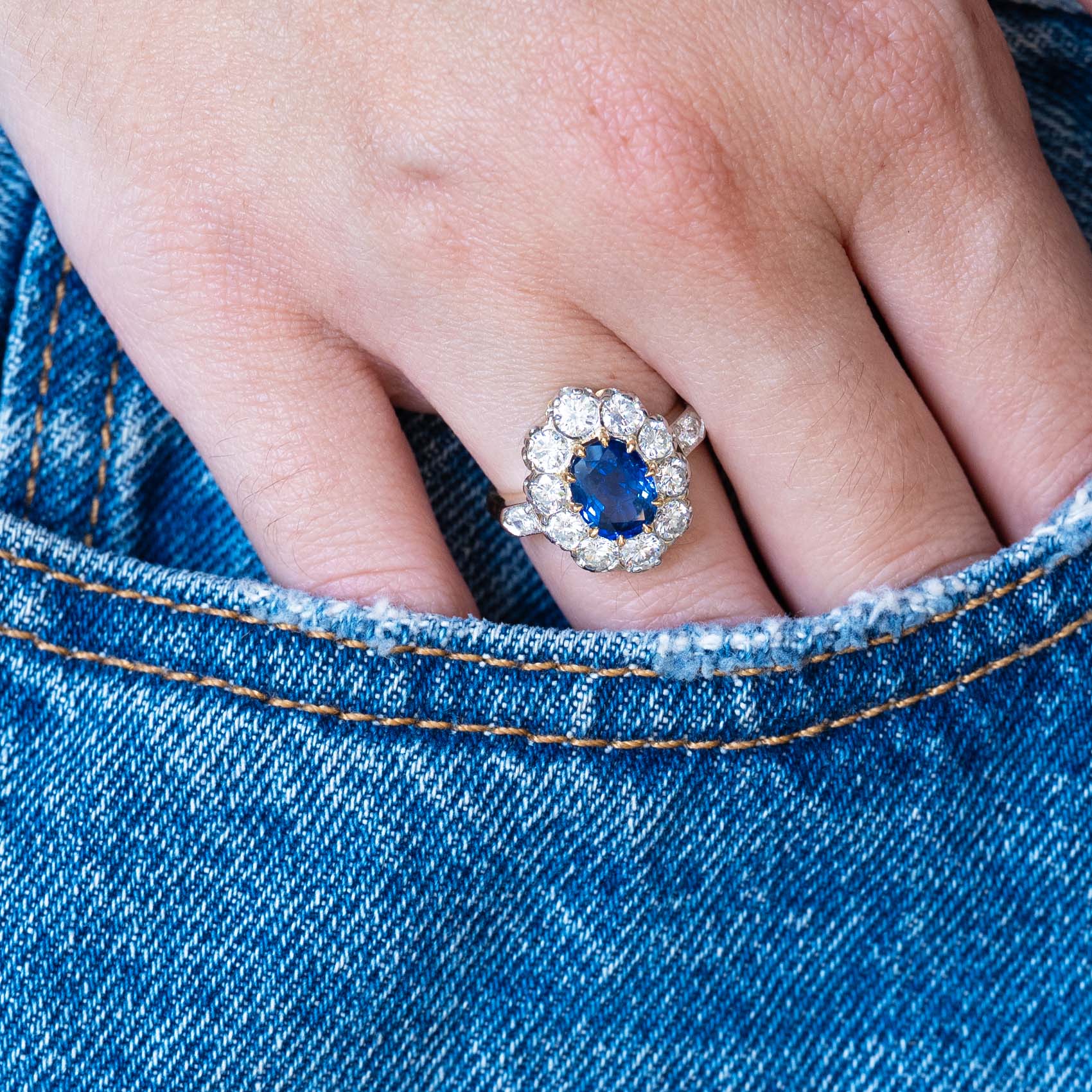 Vintage 1960s French sapphire and diamond cluster ring worn with hand resting in denim pocket.