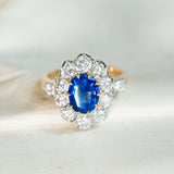 Vintage 1960s French sapphire and diamond cluster ring displayed on antique book pages with vivid sapphire centre stone.