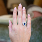 Vintage 1960s French sapphire and diamond cluster ring worn on hand with vivid blue sapphire centre stone.
