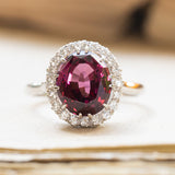 Vintage 1960s garnet and diamond cluster ring with oval garnet centre stone and diamond halo.