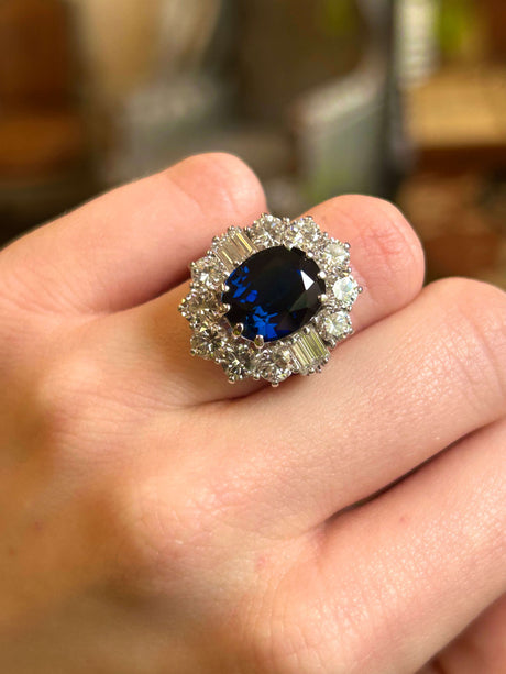 Large oval sapphire and diamond cluster ring worn on hand.