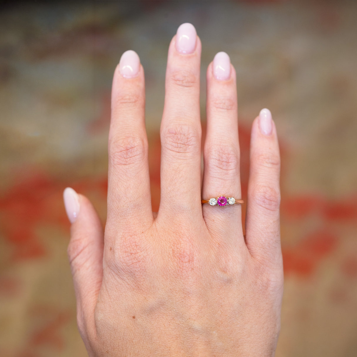 Vintage 1960s ruby and diamond three-stone ring worn on hand.