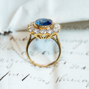 Vintage 1960s sapphire and diamond cluster ring with oval blue sapphire and diamond halo in gold setting.