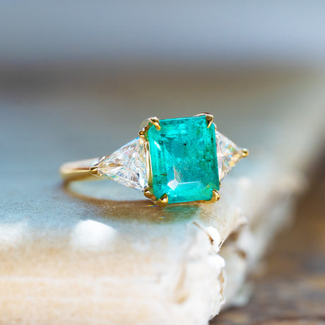 Vintage 1970s three stone ring with vivid green emerald and side diamonds.