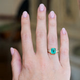 Vintage 1970s emerald and diamond three stone ring worn on hand with soft pink manicure.