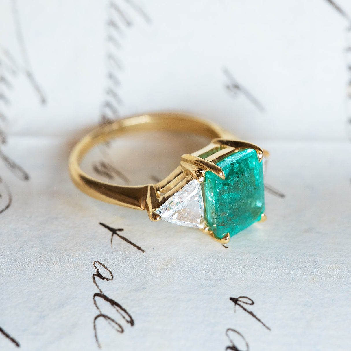 Vintage 1970s emerald and diamond three stone ring showing emerald setting and band structure.