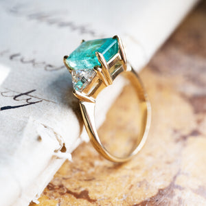 Vintage 1970s emerald and diamond three stone ring showing gold setting and diamond accents.