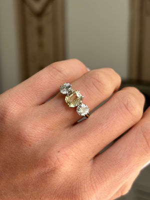 Vintage 1970s yellow sapphire and old-cut diamond three-stone engagement ring featuring a yellow sapphire centre stone and old-cut diamond accents, worn on a hand.