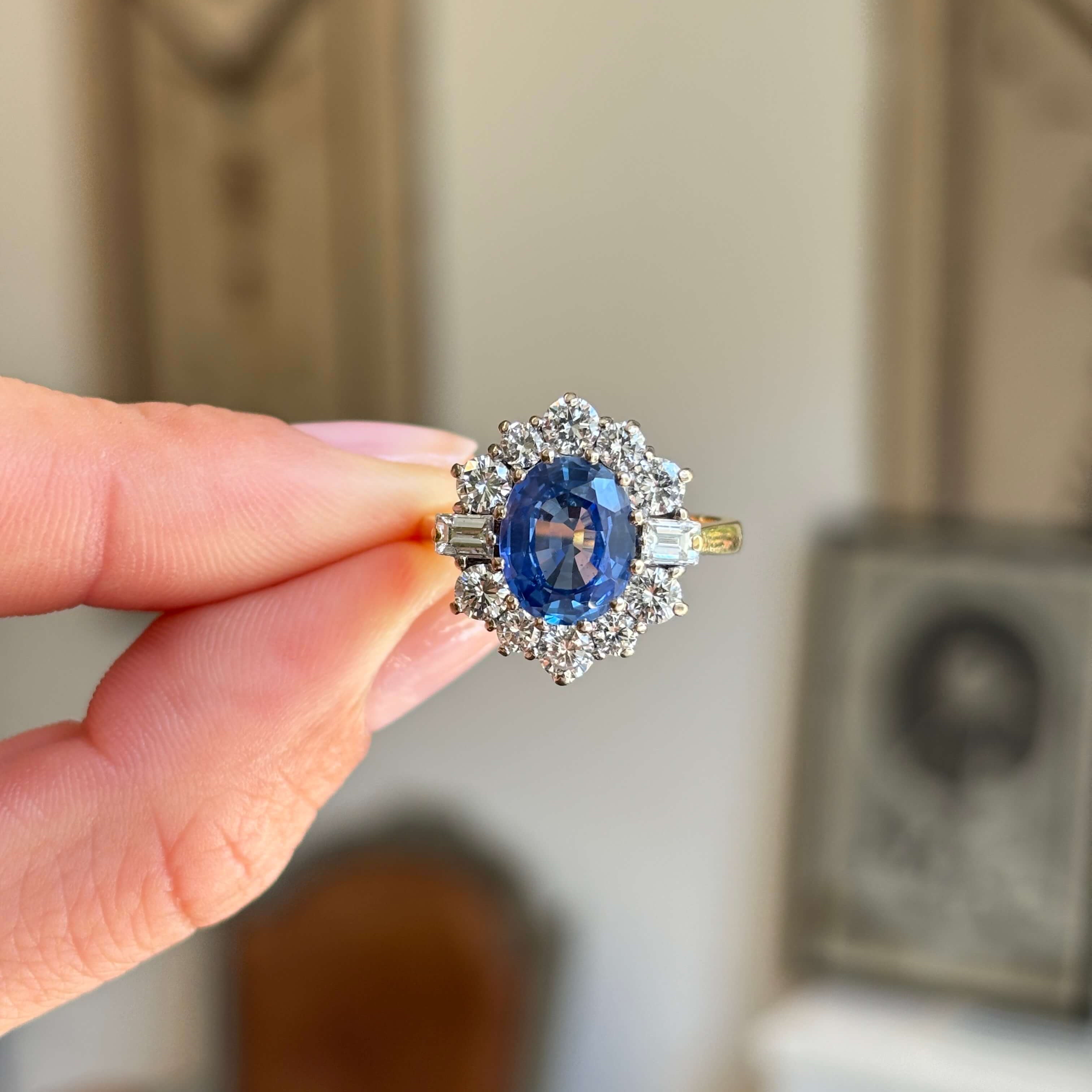 Vintage 1980s cornflower blue sapphire and diamond cluster ring featuring a cornflower blue sapphire surrounded by a halo of brilliant-cut diamonds, held by hand.