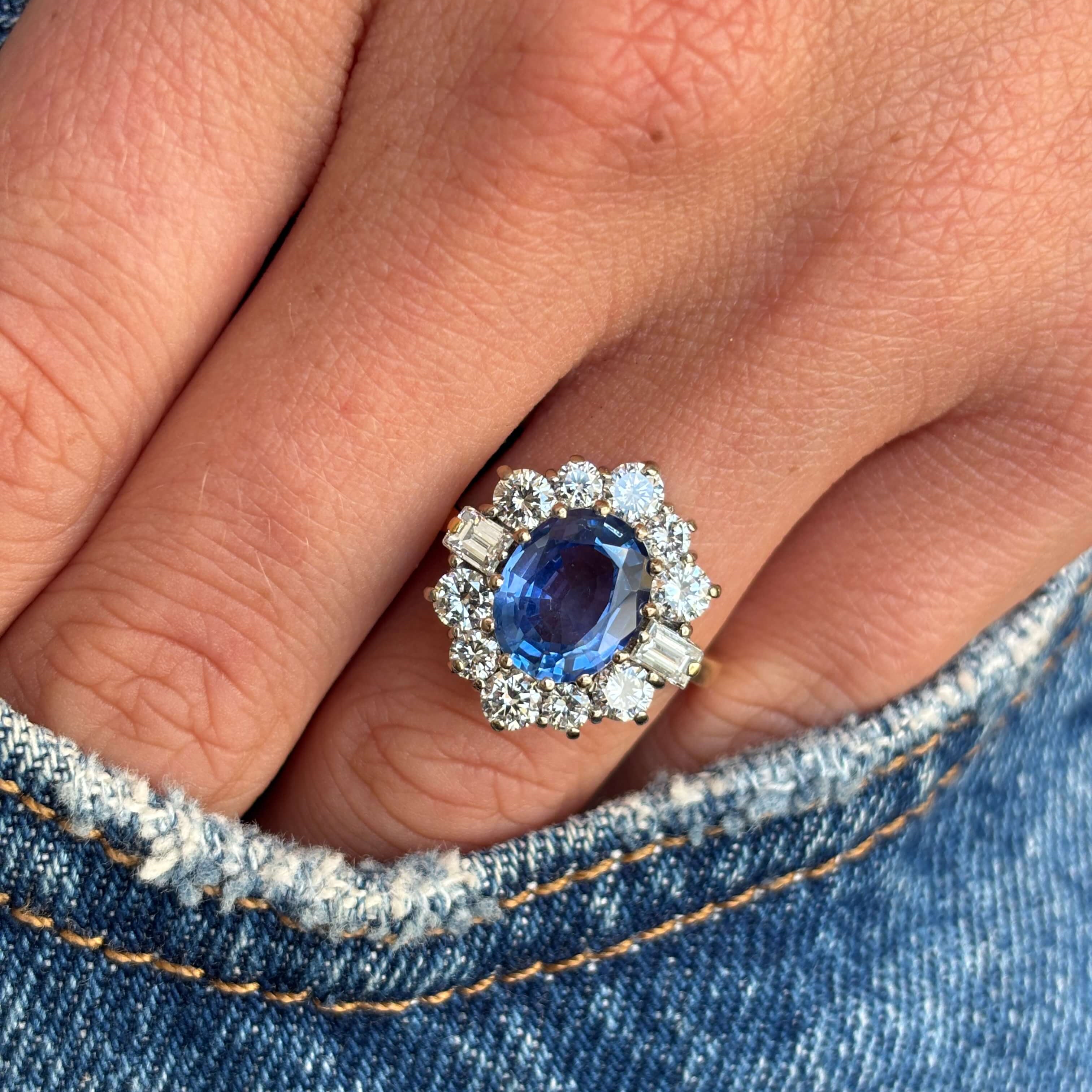 Vintage 1980s cornflower blue sapphire and diamond cluster ring with a cornflower blue sapphire centre stone and sparkling diamond halo, worn on a hand.