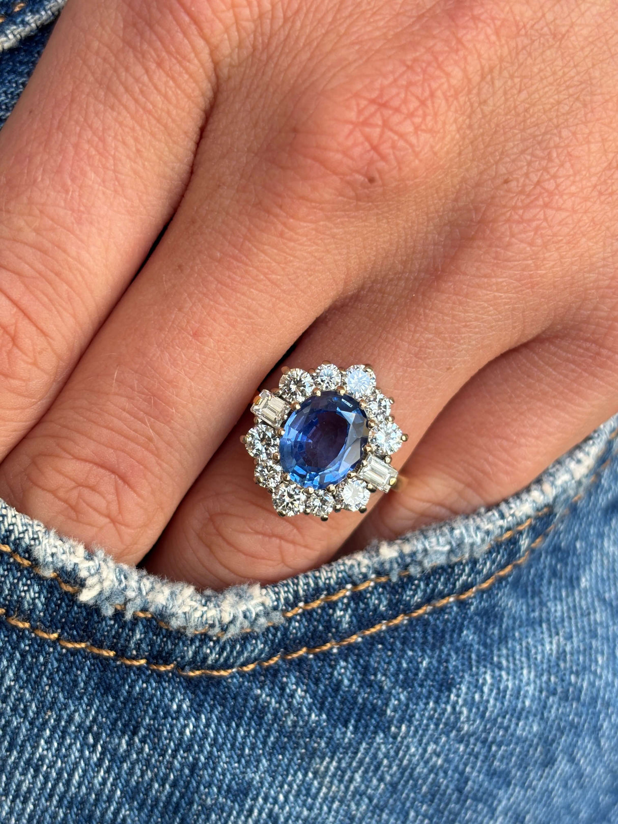 Vintage 1980s cornflower blue sapphire and diamond cluster ring with a cornflower blue sapphire centre stone and sparkling diamond halo, worn on a hand.
