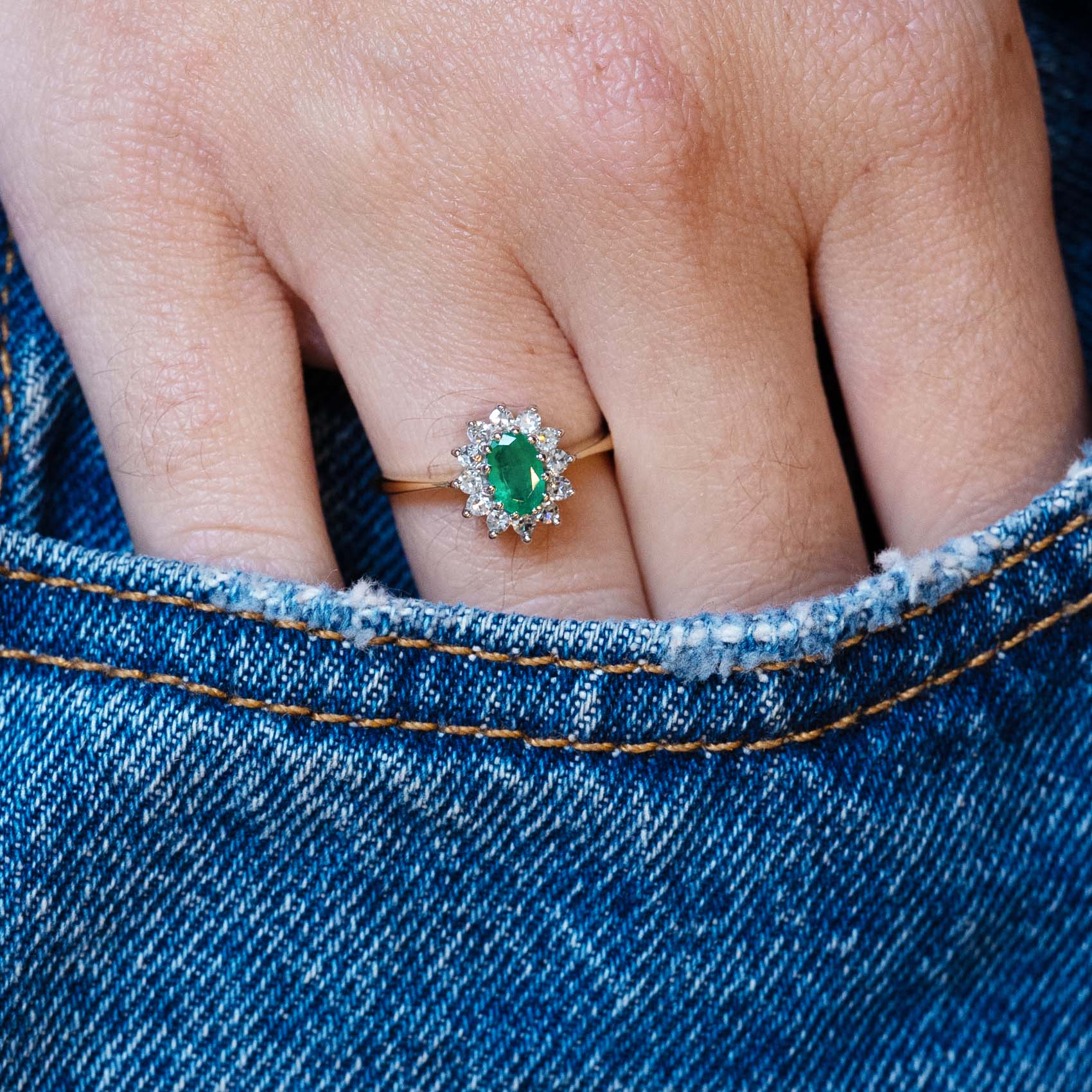 Vintage 1980s emerald and diamond cluster ring worn with hand resting in denim pocket.