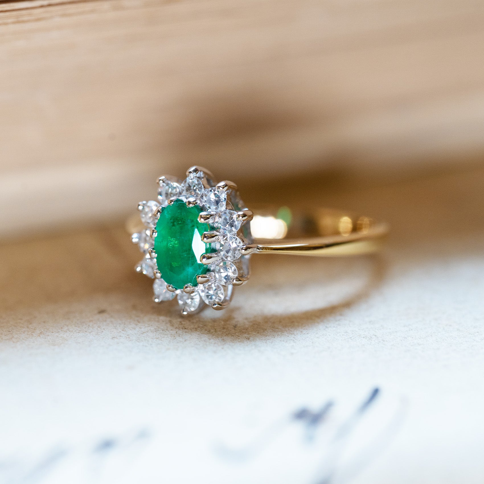 Vintage 1980s emerald and diamond cluster ring with bright oval emerald and diamond halo setting.