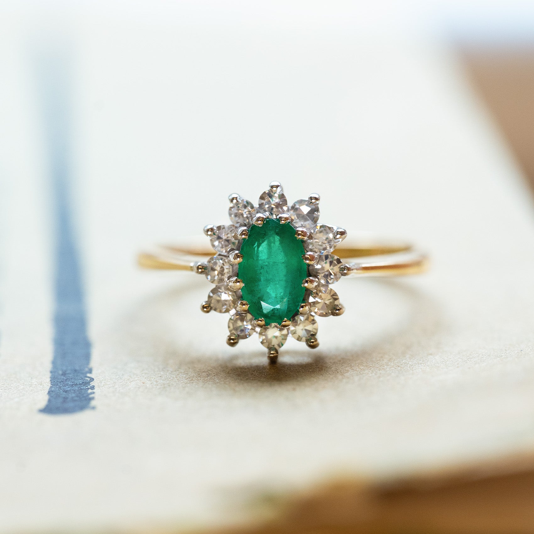 Vintage 1980s emerald and diamond cluster ring with oval emerald and diamond halo.