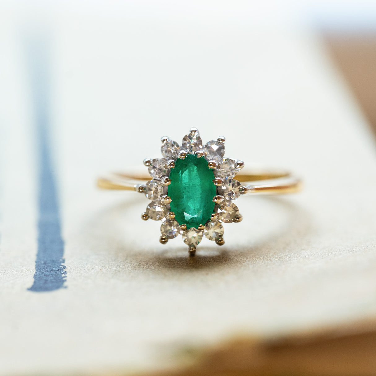 Vintage 1980s emerald and diamond cluster ring with oval emerald and diamond halo.