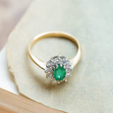 Vintage 1980s emerald and diamond cluster ring with yellow gold band and diamond surround.