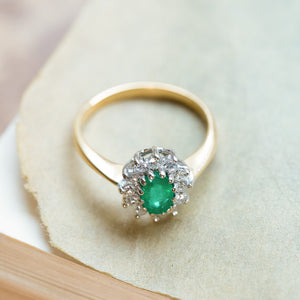 Vintage 1980s emerald and diamond cluster ring with yellow gold band and diamond surround.