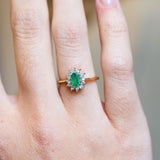 Vintage 1980s emerald and diamond cluster ring with oval emerald and delicate diamond halo.