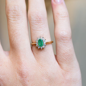 Vintage 1980s emerald and diamond cluster ring with oval emerald and delicate diamond halo.