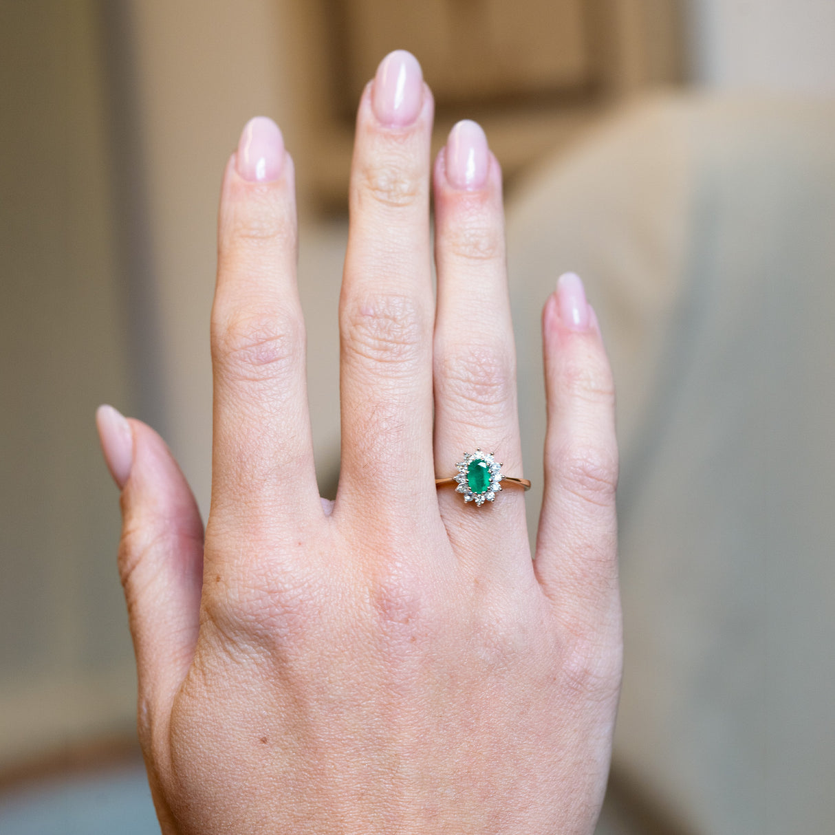 Vintage 1980s emerald and diamond cluster ring worn on hand with yellow gold band.