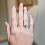 Vintage 1980s emerald and diamond cluster ring worn on hand with yellow gold band.