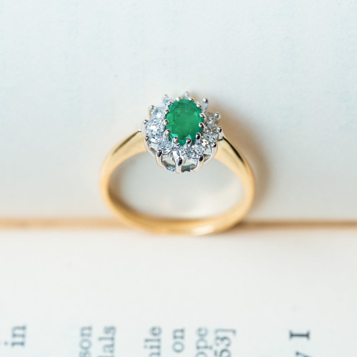 Vintage 1980s emerald and diamond cluster ring with oval emerald and polished yellow gold band.