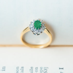 Vintage 1980s emerald and diamond cluster ring with oval emerald and polished yellow gold band.