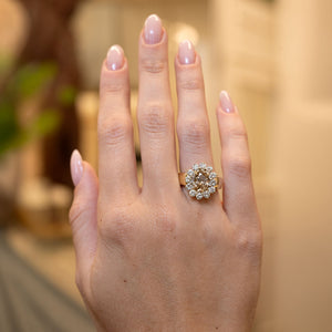 Vintage 1980s fancy coloured brown diamond cluster cocktail ring worn on the hand, featuring an oval brown diamond surrounded by brilliant-cut white diamonds in yellow gold.