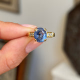 Vintage 1990s sapphire and diamond engagement ring featuring a blue sapphire centre stone accented by diamonds, held by hand.
