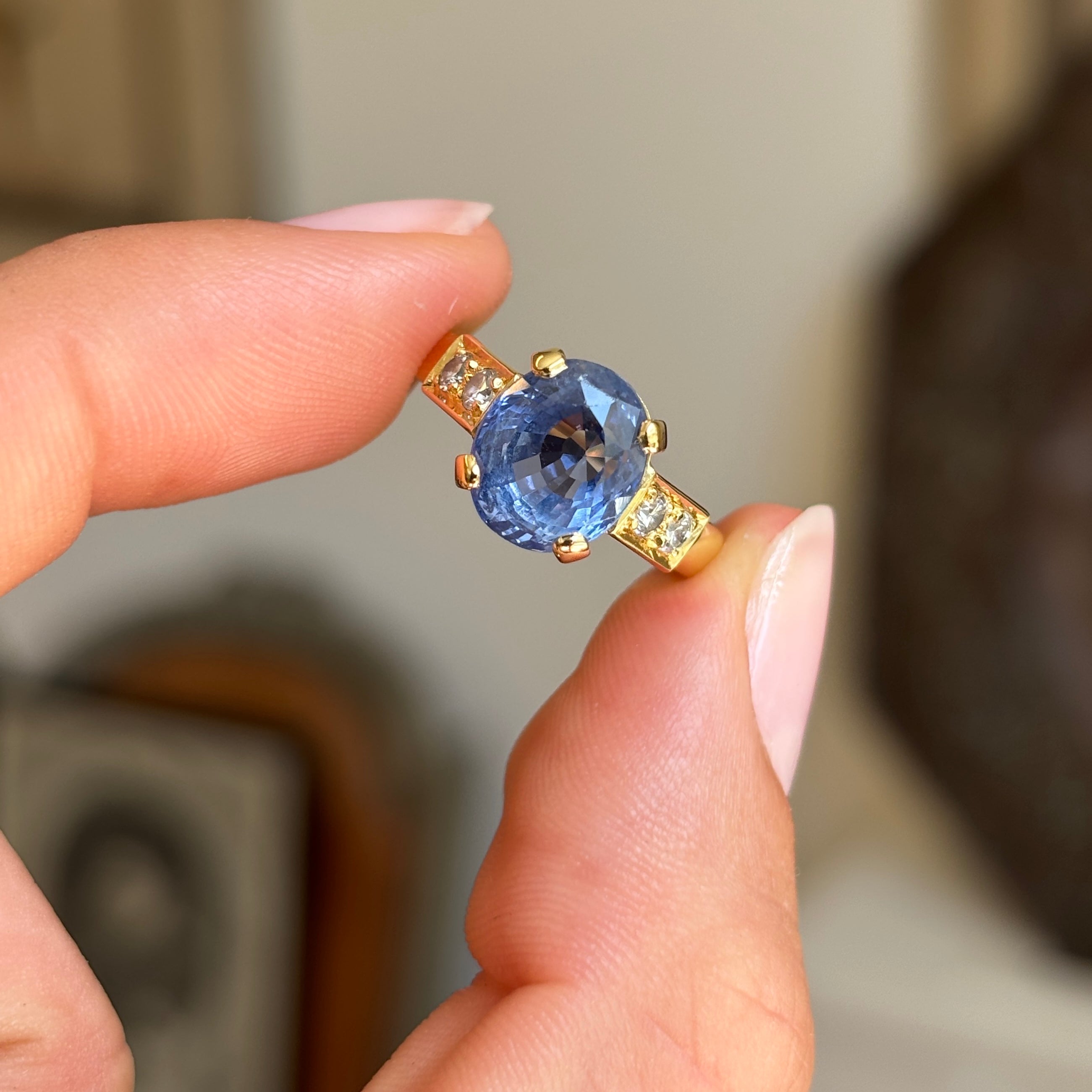 Vintage 1990s sapphire and diamond engagement ring with a blue sapphire centre and diamond accents, displayed while held by hand.