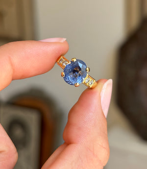Vintage 1990s sapphire and diamond engagement ring with a blue sapphire centre and diamond accents, displayed while held by hand.