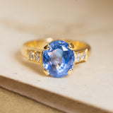 Vintage 1990s sapphire and diamond engagement ring featuring an oval-cut blue sapphire accented by diamonds in yellow gold.