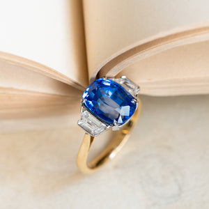 Vintage 1990s sapphire and diamond three-stone ring with rich blue sapphire and geometric diamond side stones.