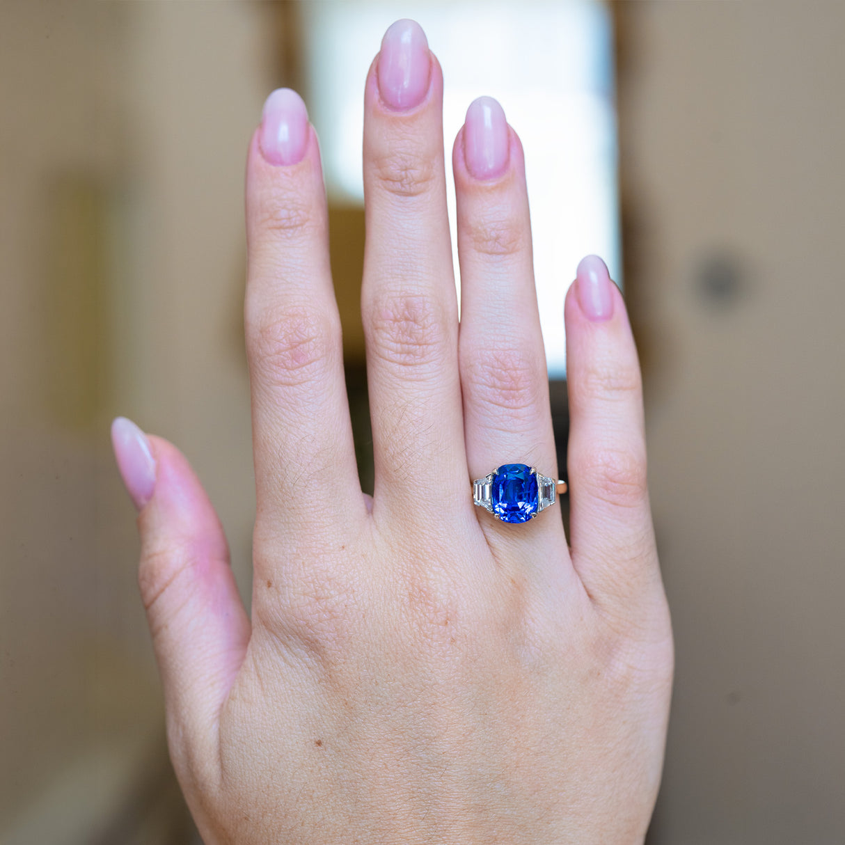 Vintage 1990s sapphire and diamond three-stone ring worn on hand with vivid blue sapphire centre stone.