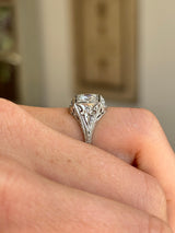 Vintage Art Deco diamond cluster ring featuring a floral-inspired diamond cluster on a hand with blurred background