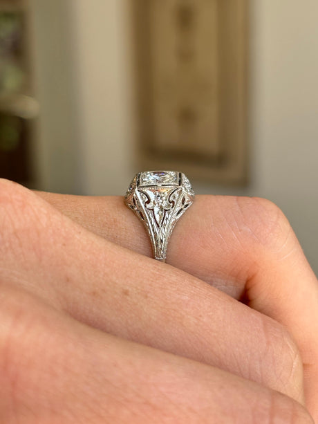 Vintage Art Deco diamond cluster ring featuring a floral-inspired diamond cluster on a hand with blurred background