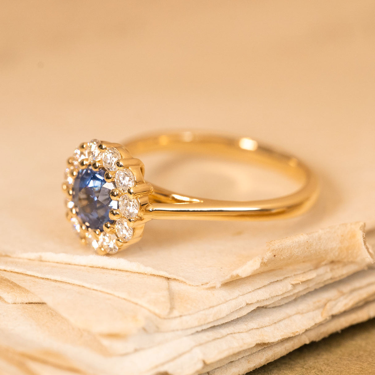 Vintage-inspired blue sapphire and diamond cluster ring showcasing a lively blue sapphire framed by brilliant-cut diamonds.