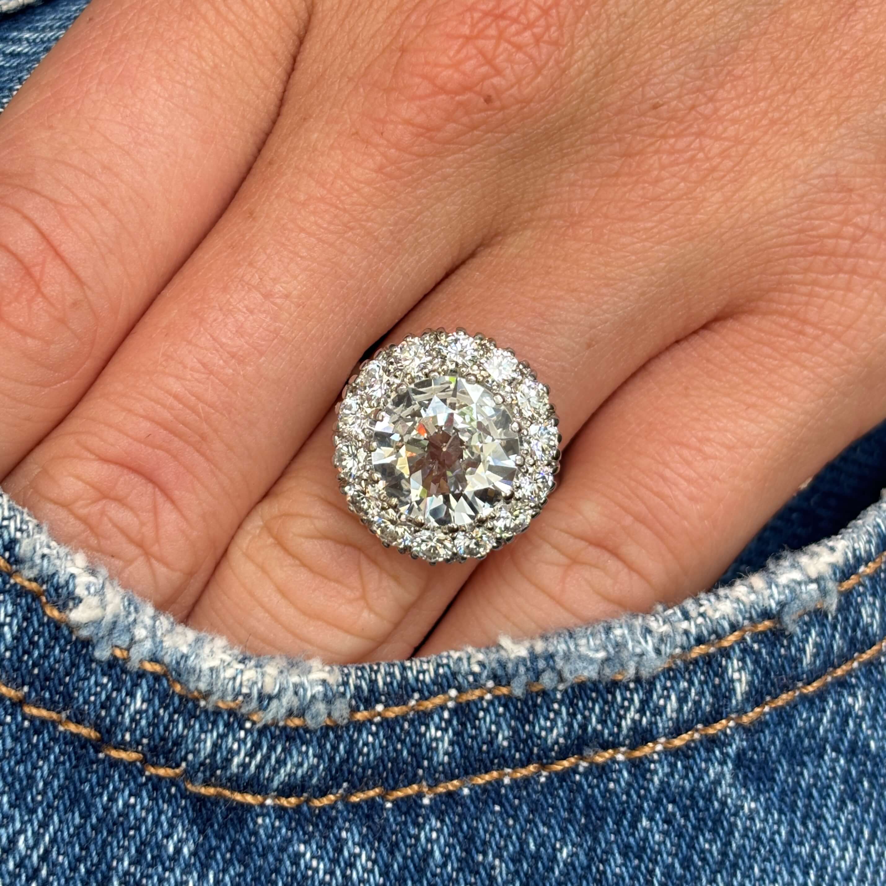 Vintage 1950s platinum diamond cluster engagement ring styled on hand against blue denim, showcasing the substantial diamond cluster, exceptional brilliance and timeless mid-century elegance.
