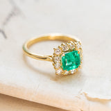 Vintage 1980s Colombian emerald and diamond cluster ring in polished yellow gold.