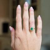 Vintage cluster ring worn on hand with vivid green centre stone and diamond cluster.