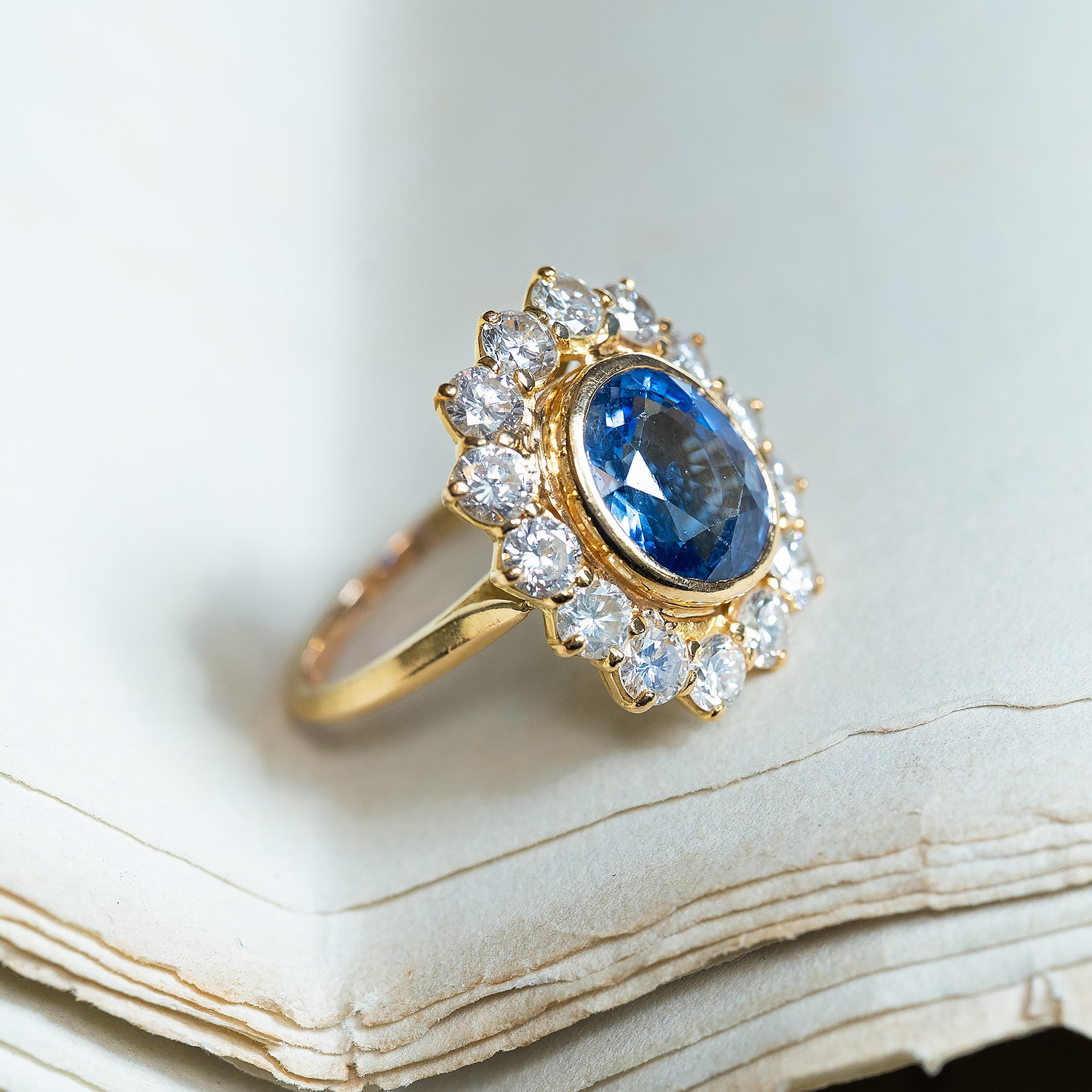 Vintage French sapphire and diamond cluster ring with deep blue sapphire and diamond halo on gold band.