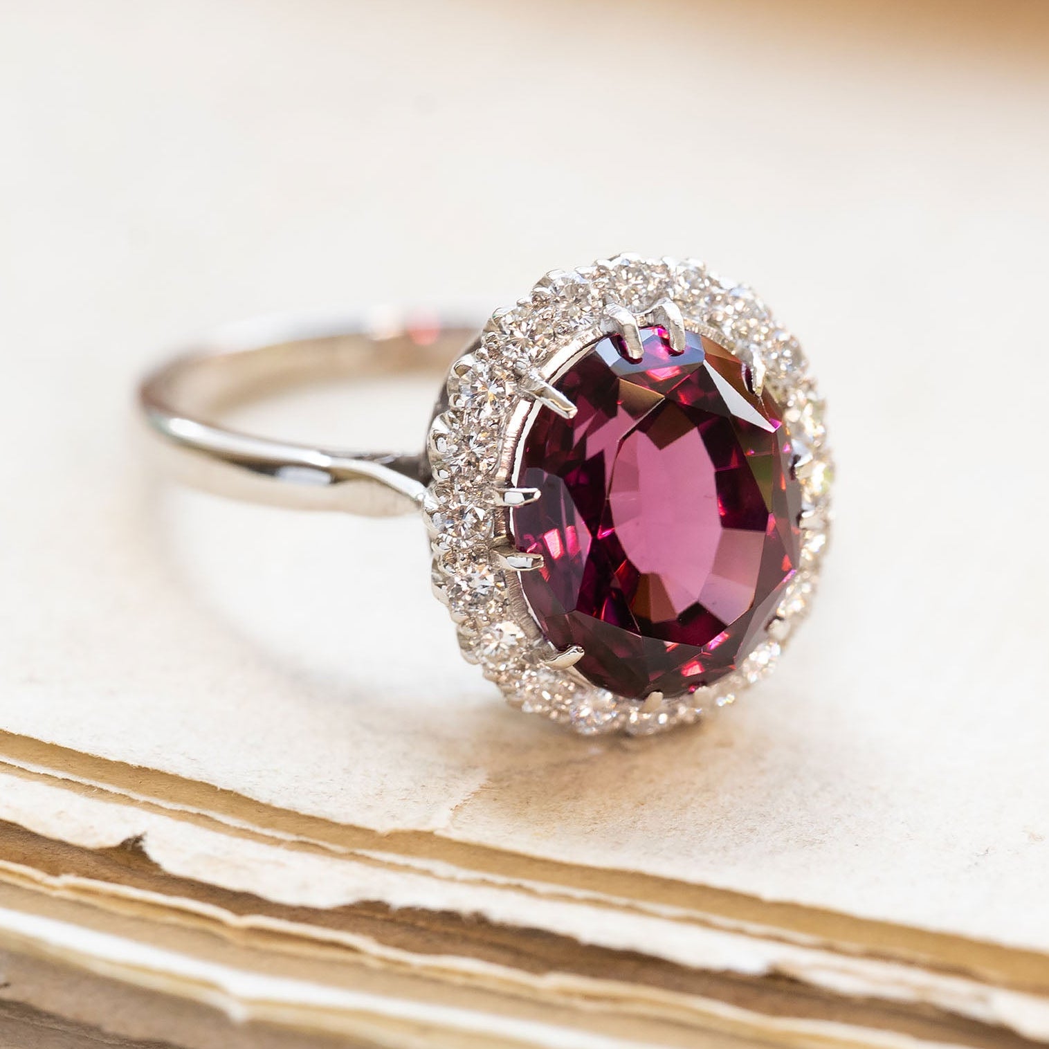 Vintage 1960s garnet and diamond cluster ring with oval garnet and diamond surround on white gold band.