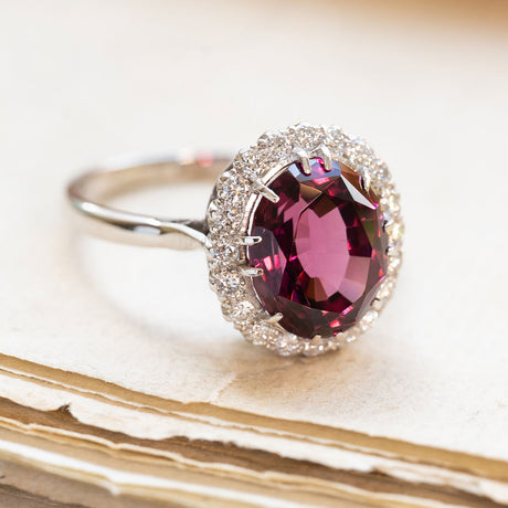 Vintage 1960s garnet and diamond cluster ring with oval garnet and diamond surround on white gold band.