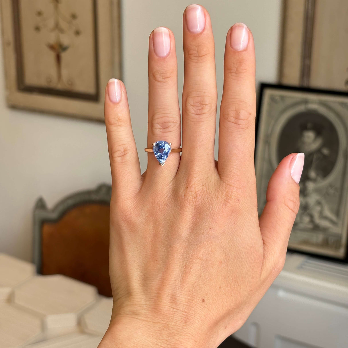Vintage inspired pear-cut bluebell sapphire solitaire engagement ring worn on hand, showcasing a vibrant bluebell sapphire in a yellow gold solitaire setting.