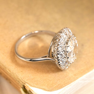Vintage old-cut diamond engagement ring with a substantial centre diamond framed by a halo of old-cut diamonds and a refined white gold band.