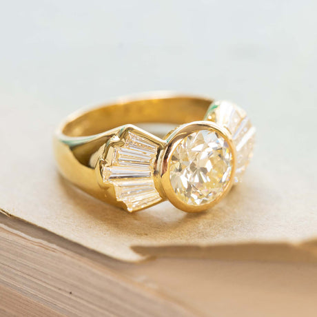 Vintage 1950s old-cut diamond fan engagement ring with wide gold band and tapered diamonds.
