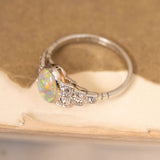 Vintage Art Deco opal and diamond cluster ring with a luminous oval opal surrounded by old-cut diamonds in an elegant platinum mount.