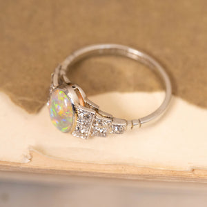 Vintage Art Deco opal and diamond cluster ring with a luminous oval opal surrounded by old-cut diamonds in an elegant platinum mount.