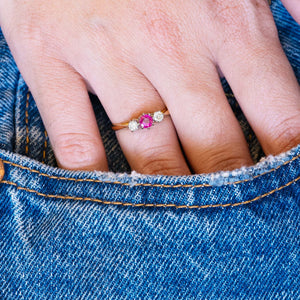 Vintage ruby and diamond three-stone ring worn with denim pocket styling.